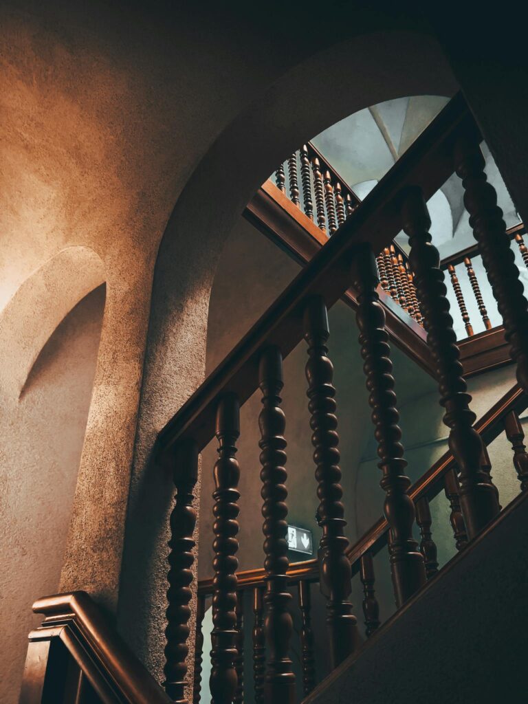 Capture of a beautifully designed wooden staircase in Zürich, showcasing artistic arches and warm tones.