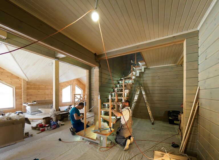 Carpenters skillfully assembling a modern wooden staircase inside a newly constructed home interior.